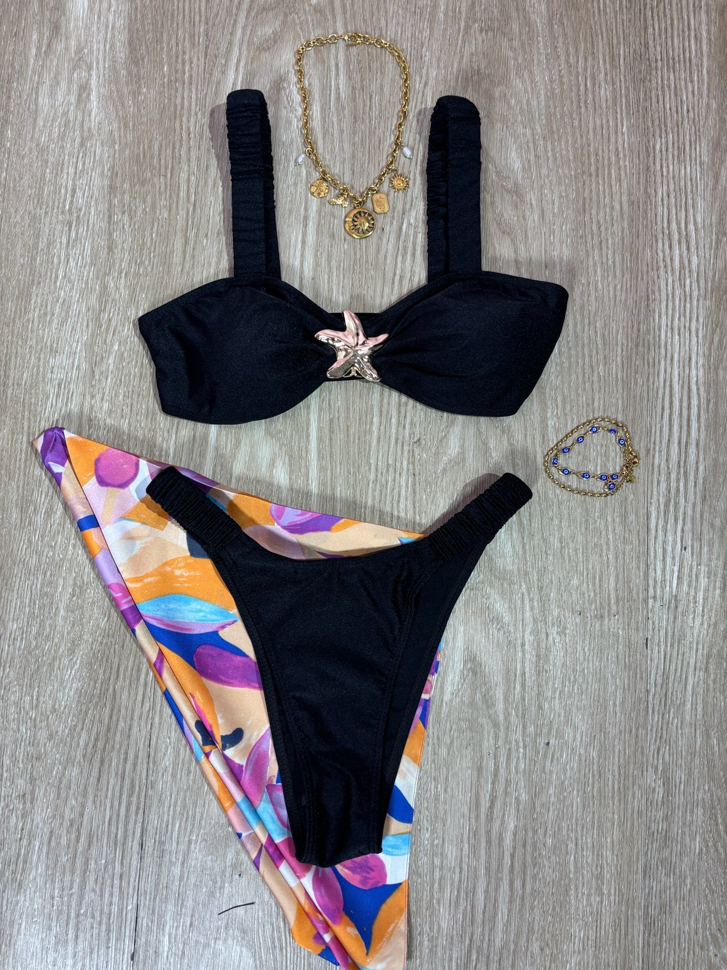 Traje de baño negro con tirantes arruchados y hebilla de estrella de mar dorada