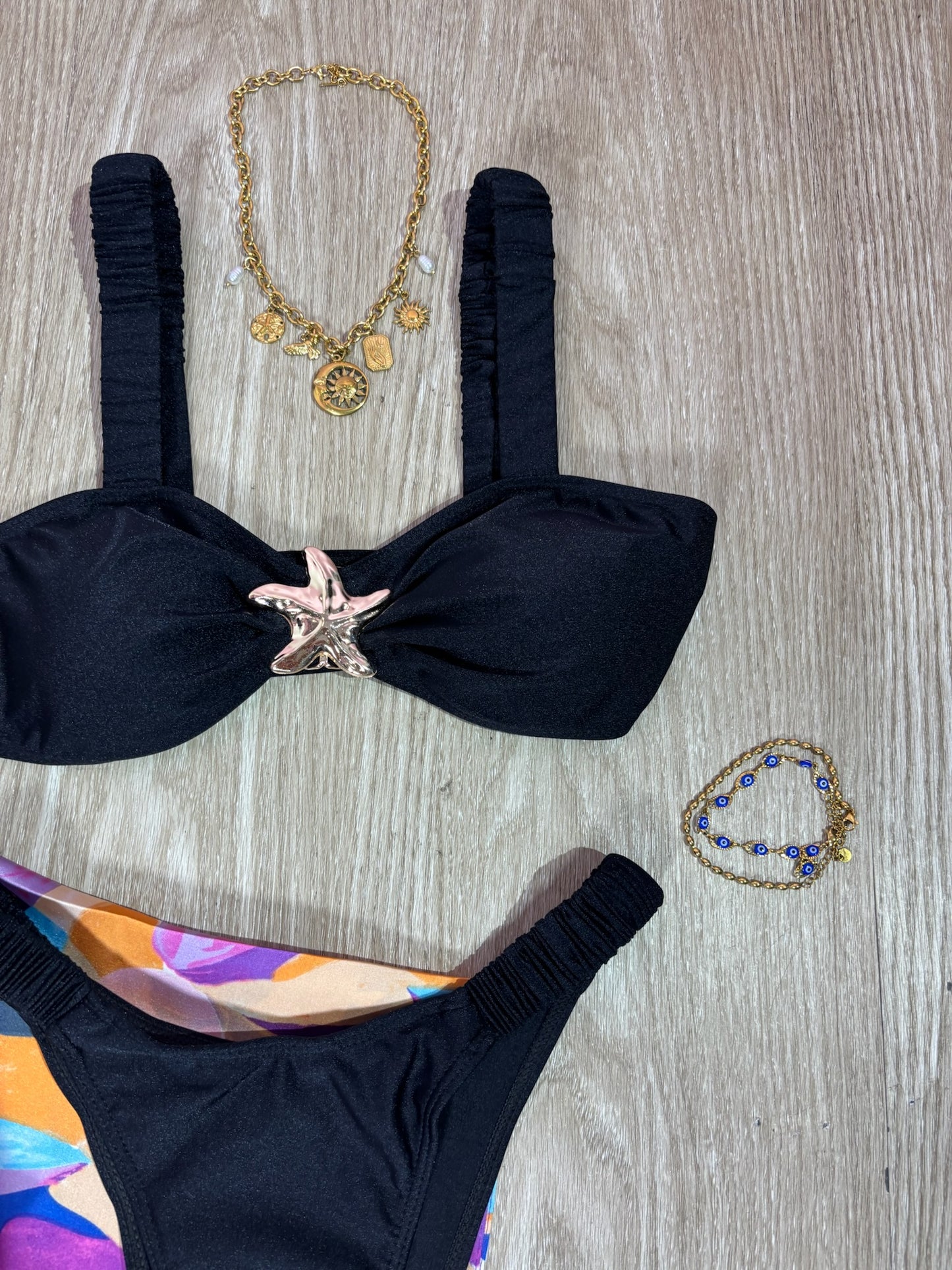 Traje de baño negro con tirantes arruchados y hebilla de estrella de mar dorada