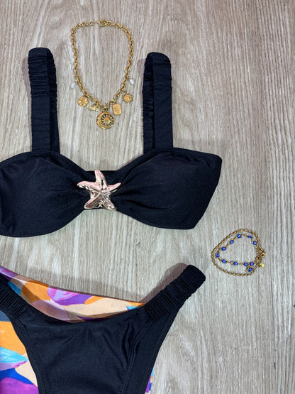 Traje de baño negro con tirantes arruchados y hebilla de estrella de mar dorada
