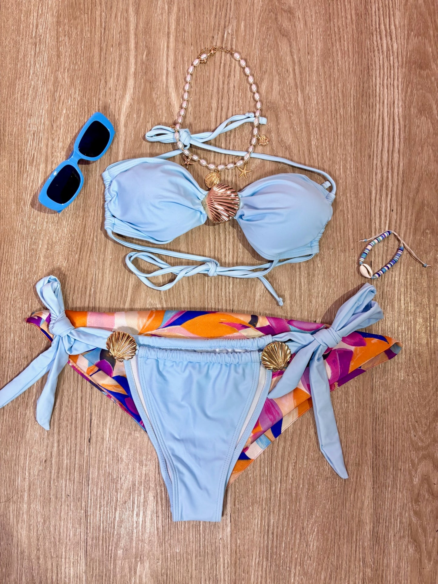 Traje de baño celeste con hebillas de concha de mar doradas y panty de amarres